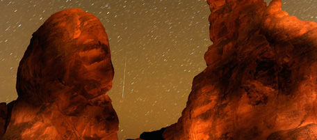 VALLEY OF FIRE STATE PARK, NV - DECEMBER 14: A Geminid meteor streaks between peaks of the Seven Sisters rock formation early December 14, 2010 in the Valley of Fire State Park in Nevada. The meteor display, known as the Geminid meteor shower because it appears to radiate from the constellation Gemini, is thought to be the result of debris cast off from an asteroid-like object called 3200 Phaethon. The shower is visible every December. (Photo by Ethan Miller/Getty Images)