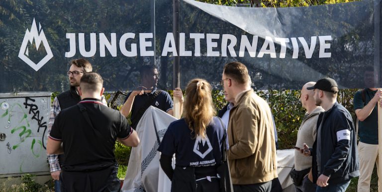 Dortmund, Deutschland. 23. April 2022. Ein Mitglied der Jungen Alternative,  der Jugendorganisation der AfD, trägt bei einer Wahlkampfveranstaltung eine  Fahne mit dem Logo der Organisation. Quelle: Alex Talash/dpa/Alamy Live  News Stockfotografie 