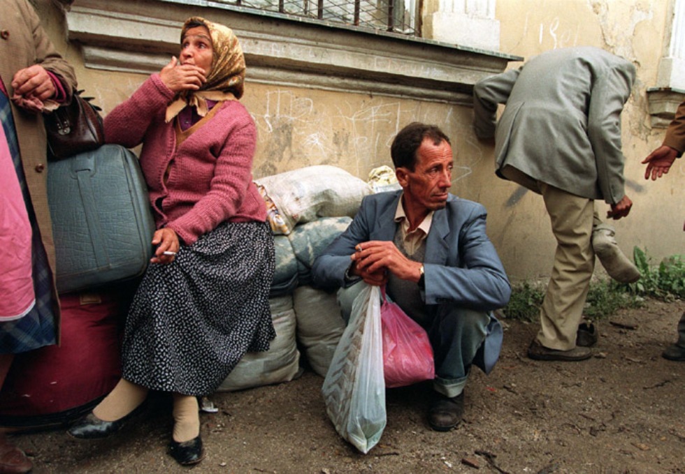 Una donna e un uomo sono seduti tra i propri bagagli dopo essere stati scacciati dalla città di Banja Luka