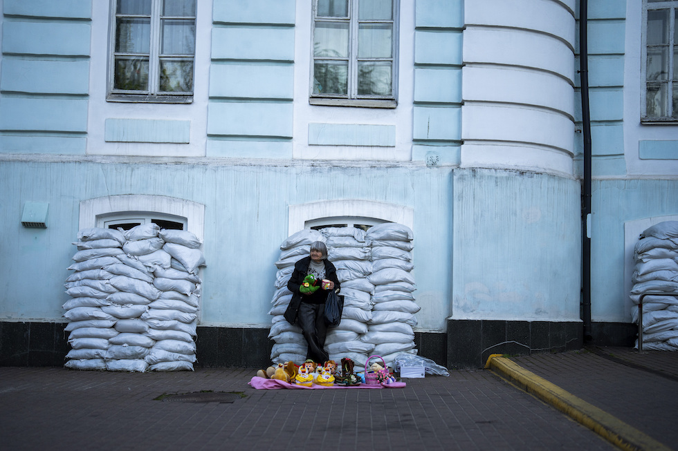 Una donna davanti a finestre protette con sacchi di sabbia a Kiev