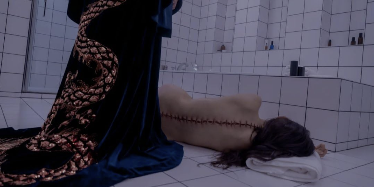 Una scena del film The Substance in cui la protagonista è sdraiata a terra, in un bagno, con una lunga cicatrice sulla schiena