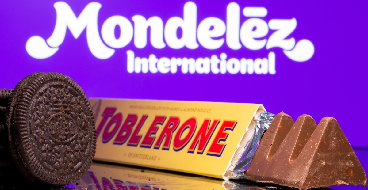Un biscotto Oreo e del cioccolato Toblerone fotografati davanti al logo di Mondelez International (REUTERS/ Dado Ruvic/ Illustration)