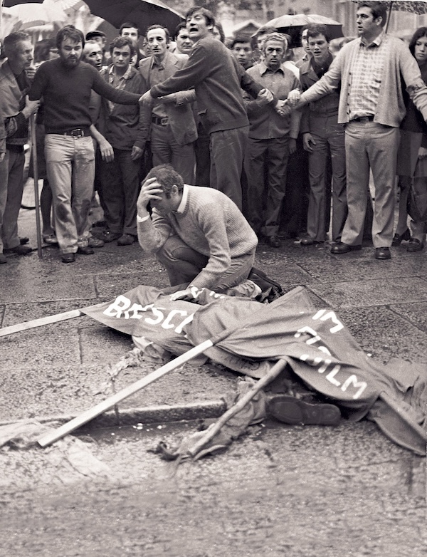 Una foto di Arnaldo Trebeschi vicino al corpo del fratello coperto da uno striscione, dopo la strage di piazza della Loggia