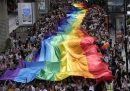 Decine di manifestanti reggono una grossa bandiera arcobaleno durante il Pride, l'evento con cui si rivendica la tutela dei diritti della comunità LGBTQ+