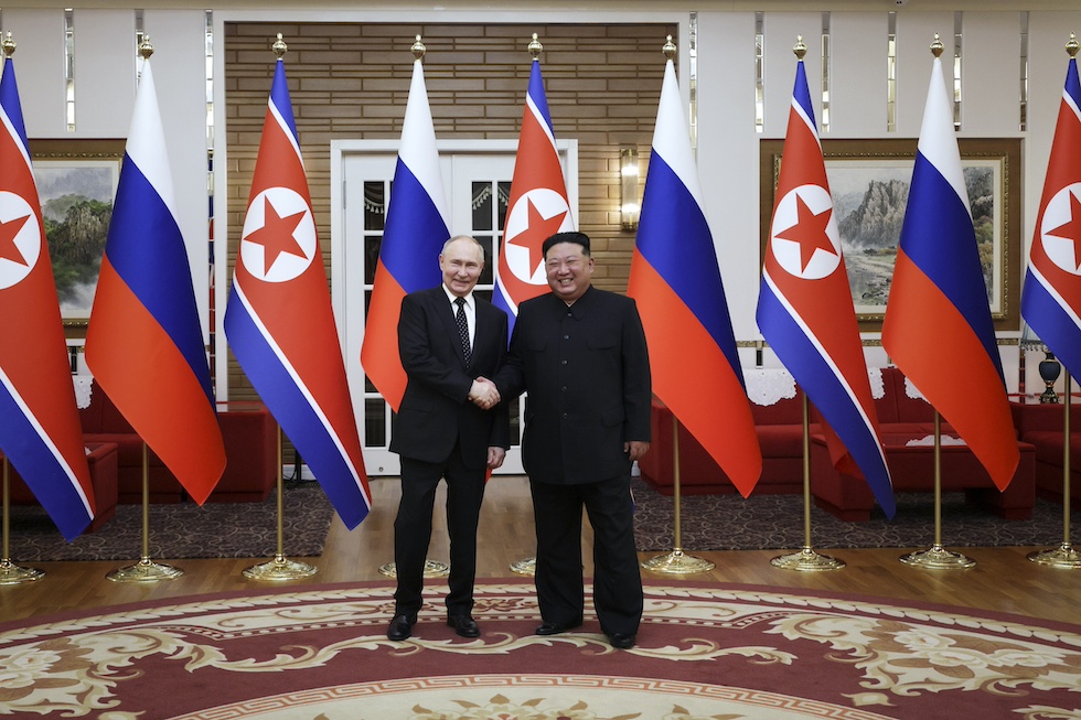 Il presidente russo Vladimir Putin e il leader nordcoreano Kim Jong Un si stringono la mano sorridendo durante la cerimonia di benvenuto, 19 giugno 2024 (Gavriil Grigorov, Sputnik, Kremlin Pool Photo via AP)