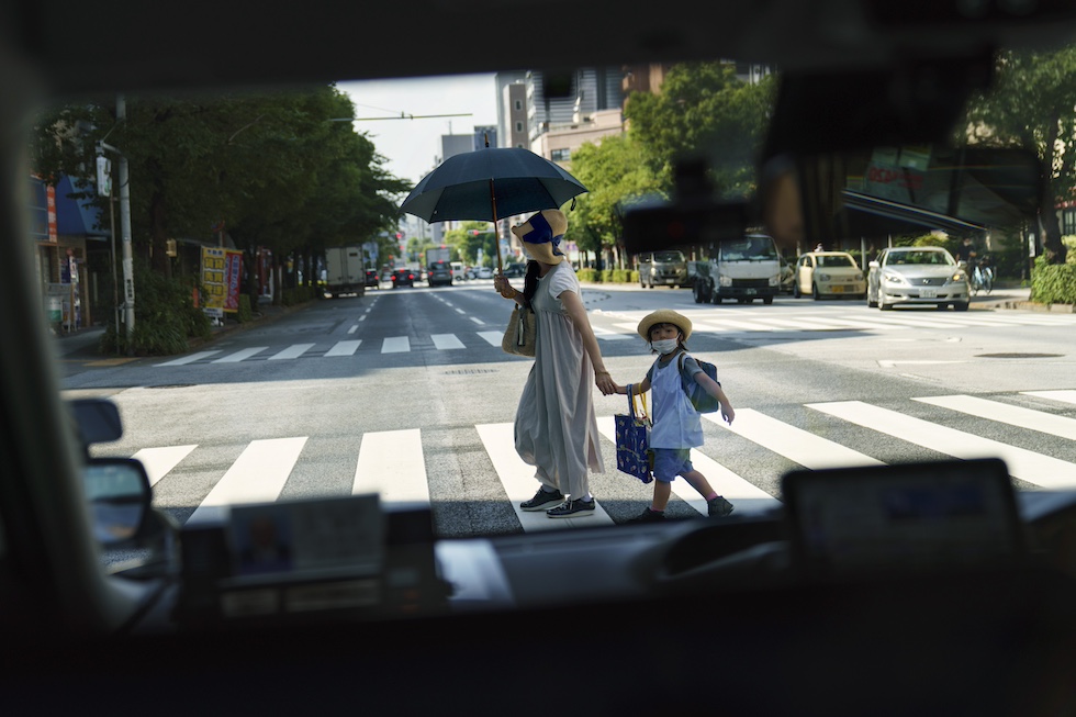 La foto di una donna con un bambino che attraversa una strada di Tokyo, 19 luglio 2021 (AP Photo/David Goldman)