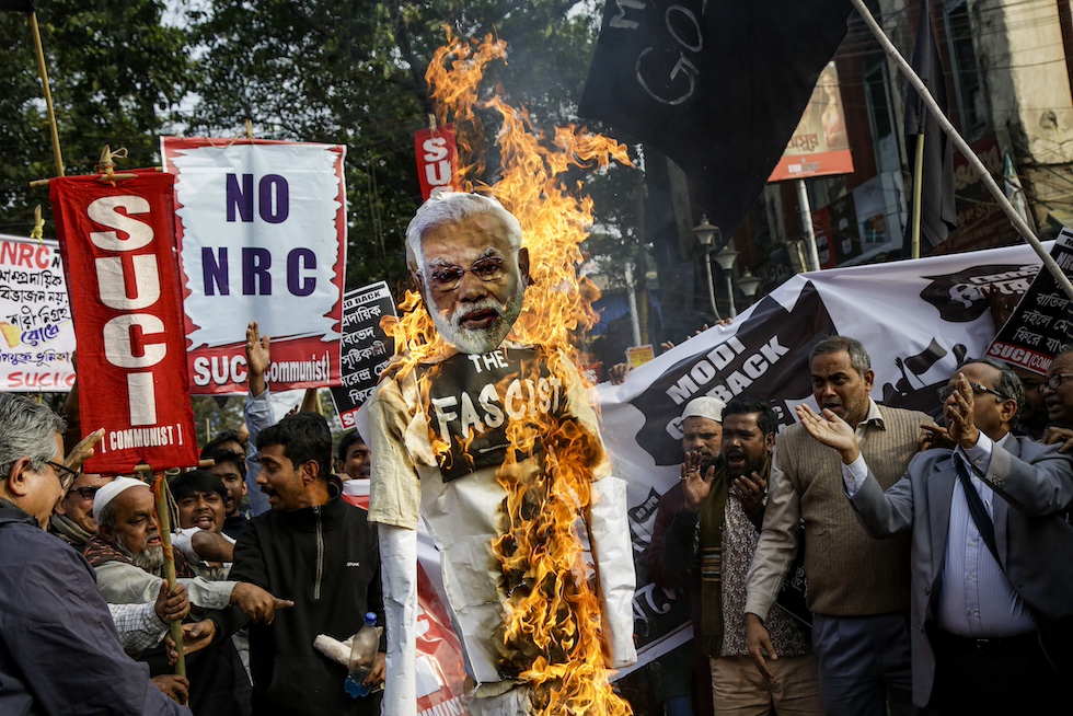 Una foto di alcuni manifestanti bruciano un cartellone con la faccia di Narendra Modi durante una protesta contro una legge molto contestata sulla cittadinanza, 11 gennaio 2020 (AP Photo/Bikas Das)