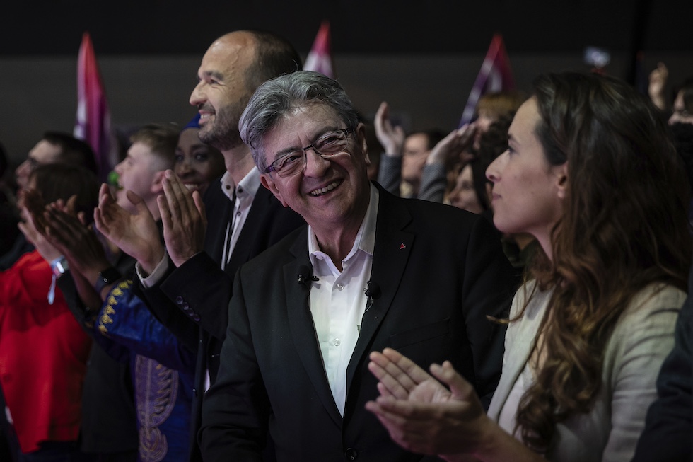 Jean-Luc Melenchon che sorride guardando a lato in una folla di persone che applaudono