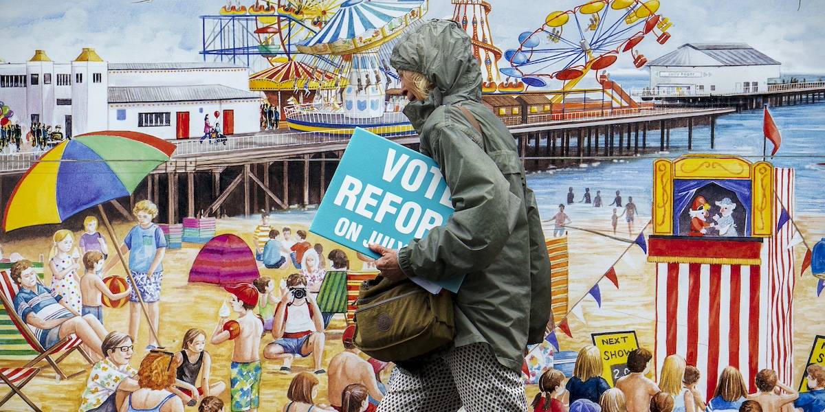 Una donna con un manifesto elettorale di Reform UK, il partito populista di destra di Nigel Farage, a Clacton-on-Sea, in Inghilterra (AP Photo/Vadim Ghirda)