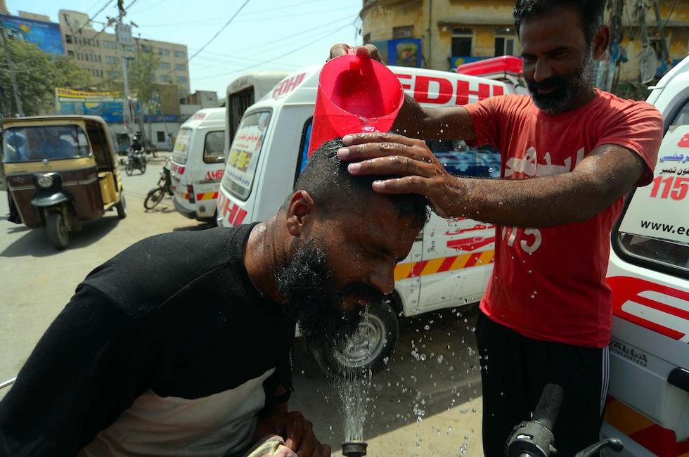 Un volontario della fondazione Edhi rinfresca un passante a Karachi, il 28 giugno