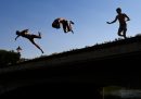 Tre ragazzi si tuffano in un laghetto della città, dove in questi giorni le temperature hanno superato i 39 °C. La foto è di martedì.