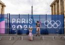 due bambini davanti a una transenna con uno striscione delle olimpiadi di parigi, con la tour eiffel sullo sfondo