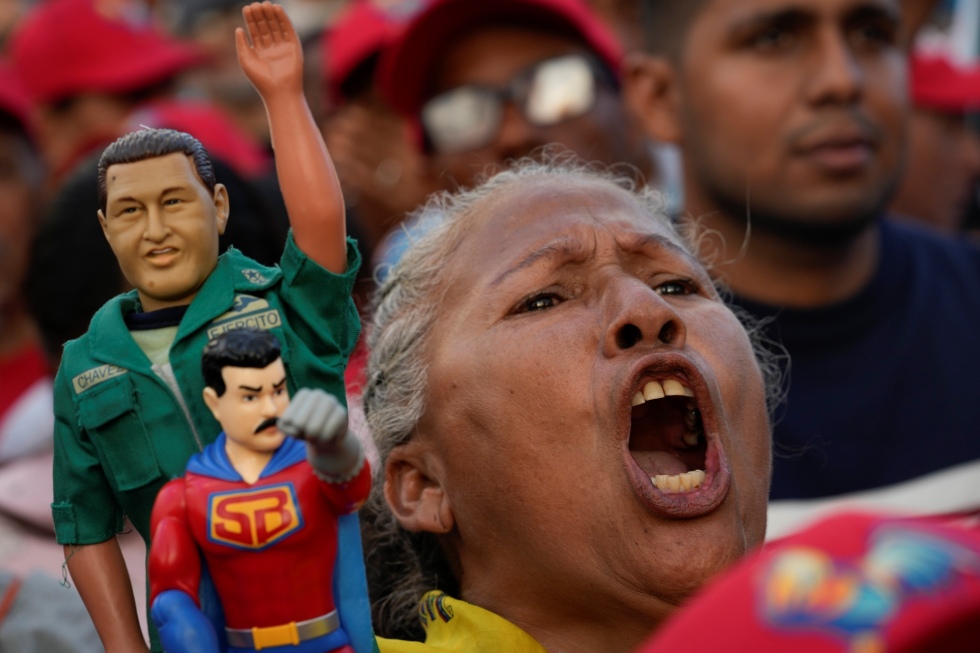 Una sostenitrice del chavismo con dei pupazzetti che rappresentano Chávez e "Superbigote", un supereroe ispirato a Maduro, durante un comizio elettorale