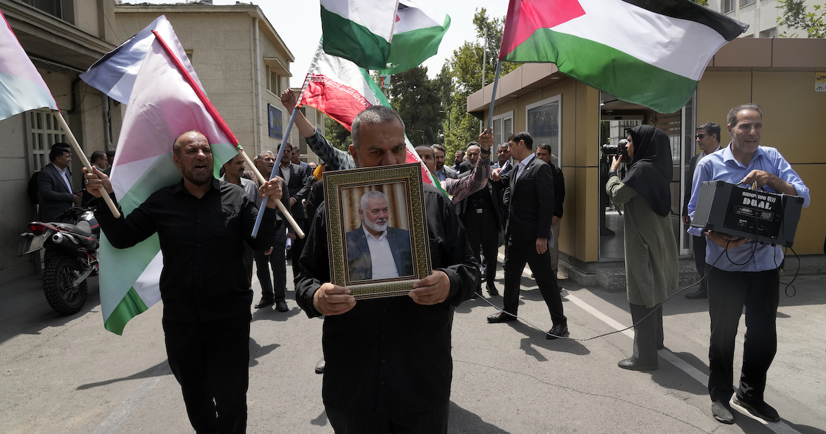 Un uomo sfila a Teheran con una foto di Ismail Haniyeh