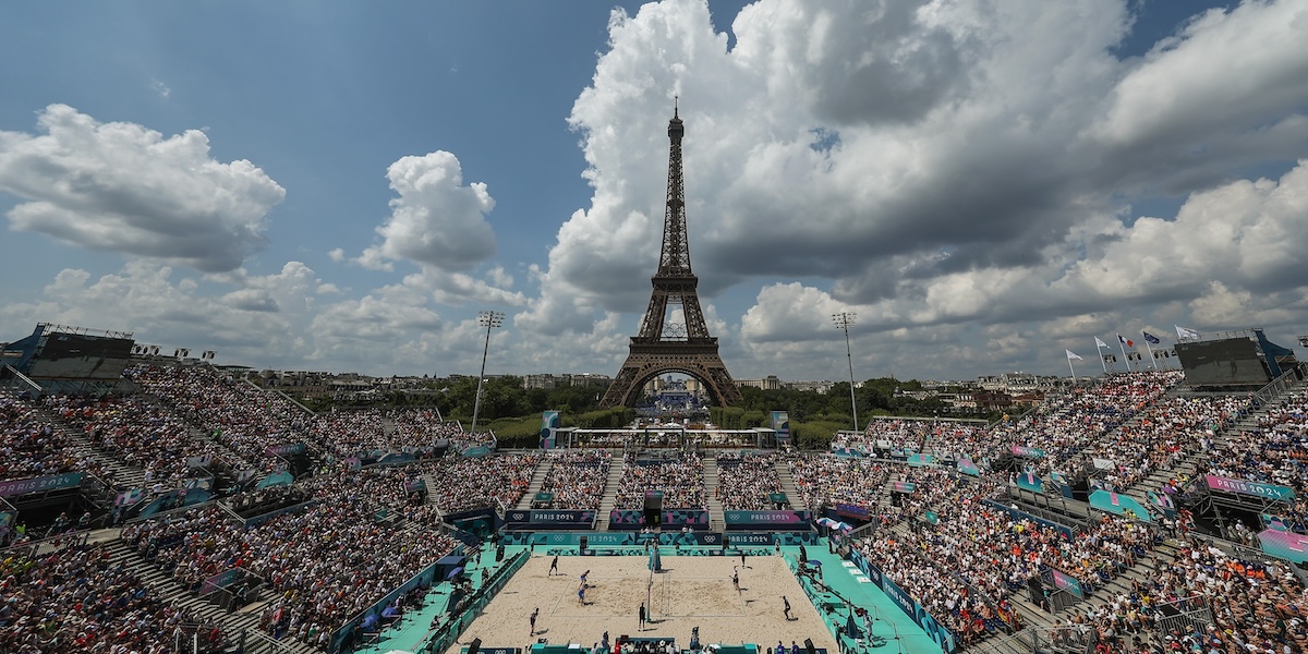 Il campo da beach volley delle Olimpiadi di Parigi durante una partita: sullo sfondo c'è la Torre Eiffel e gli spalti sono pieni di persone