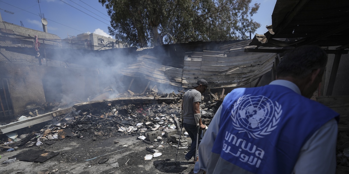 Alcune persone tra i detriti di una scuola gestita dall'UNRWA distrutta da un bombardamento israeliano a Nuseirat, nella Striscia di Gaza, lo scorso 14 maggio (AP Photo/ Abdel Kareem Hana, file)