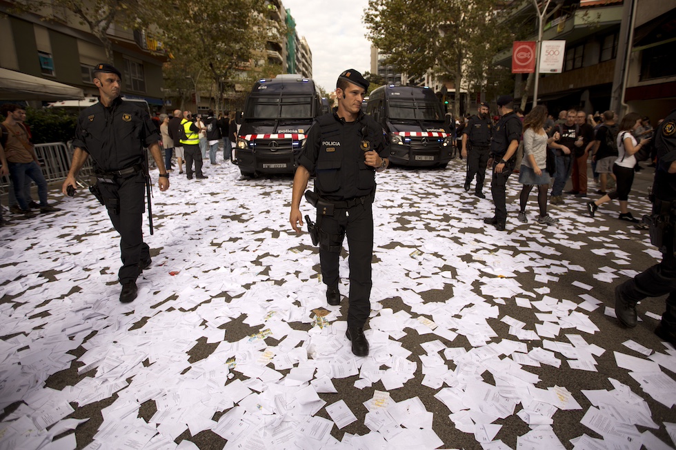 Mossos d'Esquadra camminano su una strada piena di schede elettorali dopo il referendum del 2017, (AP Photo/Emilio Morenatti)