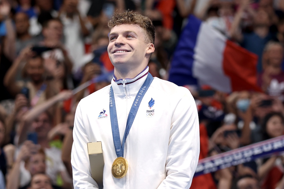 Leon Marchand sorride con la medaglia d'oro al collo durante una premiazione 