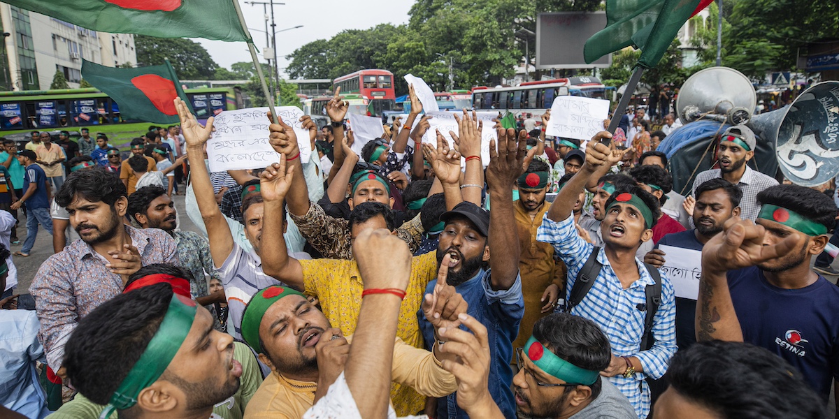 Un piccolo gruppo di persone con bandiere e bandane con la bandiera del Bangladesh, verde con un cerchio rosso al centro