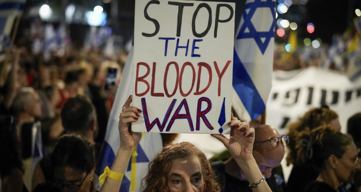 Una manifestante contro la guerra a luglio a Tel Aviv, con un cartello con scritto: "Fermate questa guerra sanguinosa"