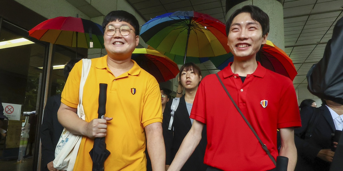 So Sung-uk, a sinistra, e Kim Yong-min, a destra, escono dall'edificio della Corte Suprema tenendosi per mano dopo aver vinto la causa contro il Servizio di assicurazione sanitaria nazionale (Suh Dae-yeon/Yonhap via AP)