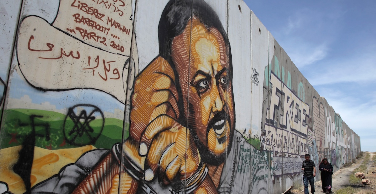 Due persone passano davanti a un murale dedicato a Marwan Barghouti a Ramallah, in Cisgiordania, il 25 maggio del 2011 (REUTERS/ Baz Ratner)