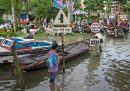 persone con l'acqua al ginocchio in mezzo a dei cartelli stradali e a delle barche