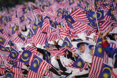 Gli studenti sventolano bandiere nazionali durante la parata della Festa nazionale dell'indipendenza della Malaysia