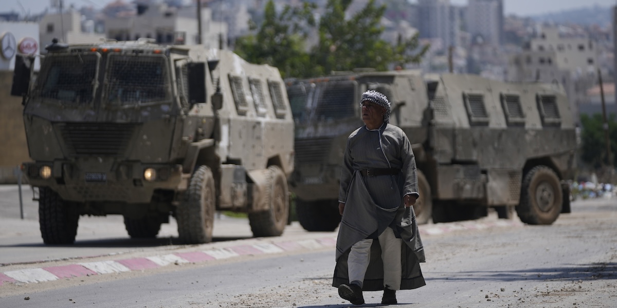 Un uomo palestinese vicino a un convoglio di carri armati israeliani (AP Photo/Nasser Nasser)