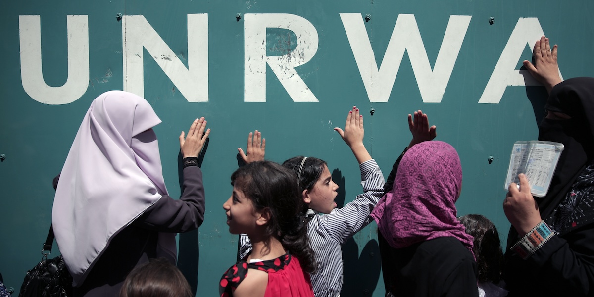 Donne e bambini sotto a una sede della UNRWA