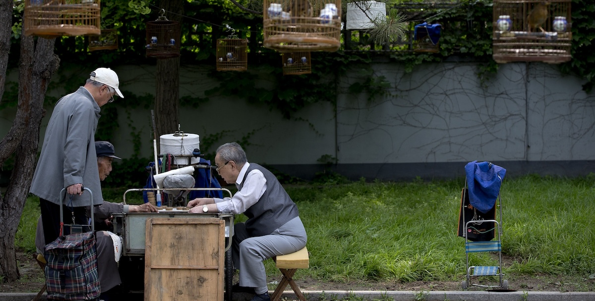 Alcune persone anziane mentre giocano a scacchi cinesi in un parco di Pechino (AP Photo/Andy Wong)