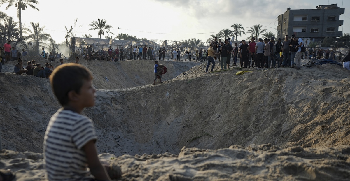 Un bambino palestinese davanti al cratere causato da un attacco israeliano il 10 settembre nella zona di Al Mawasi, nel sud della Striscia di Gaza (AP Photo/Abdel Kareem Hana)