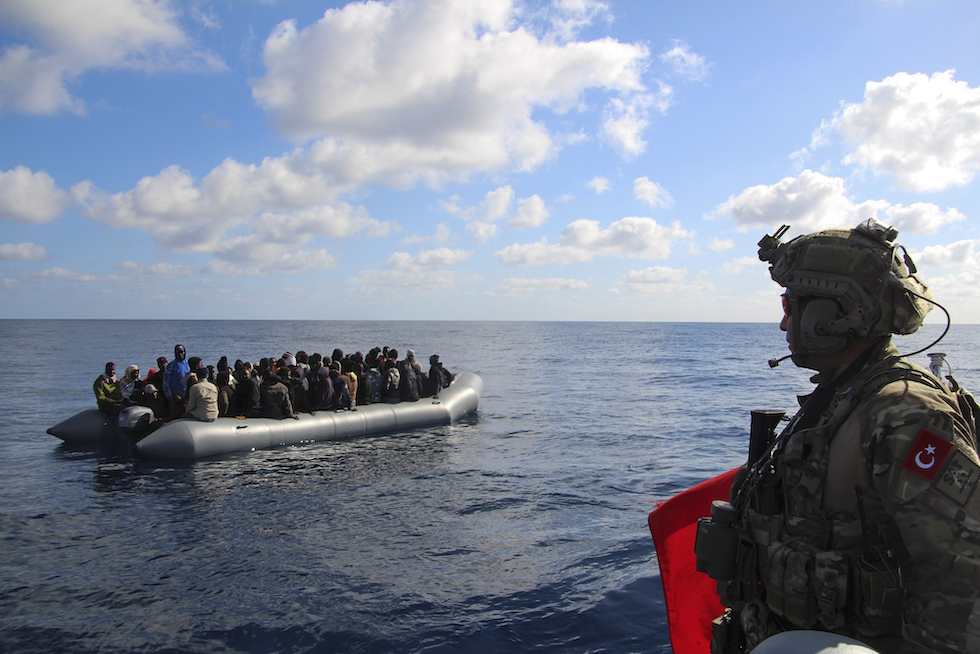 La foto di una nave militare turca che blocca un gommone sovraffollato di persone migranti nel Mediterraneo 