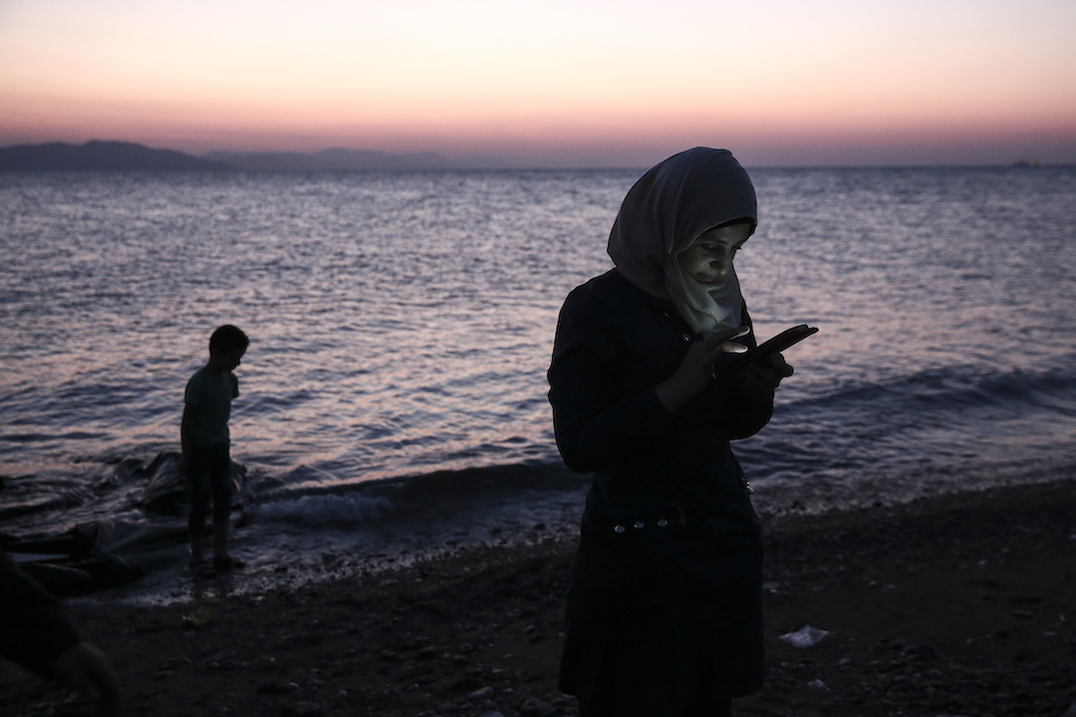 Una foto di una donna controlla il suo telefono dopo essere arrivata sull'isola greca di Kos a bordo di un gommone, 12 agosto 2015