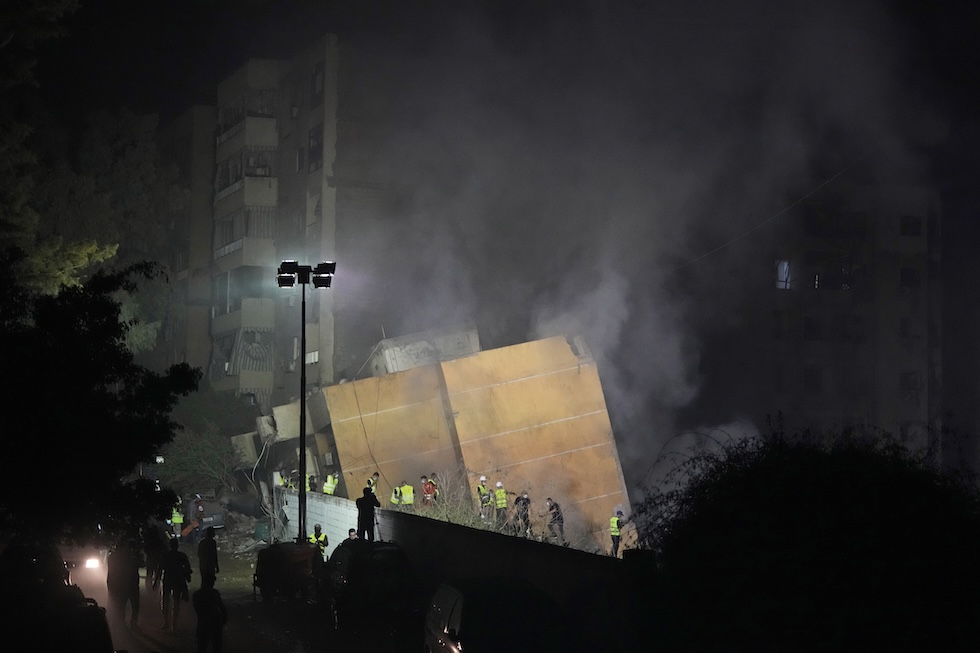 Soccorritori attorno a un edificio colpito dai bombardamenti israeliani (AP Photo/Hassan Ammar)