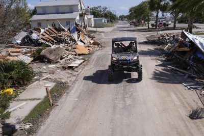 Un veicolo su una strada con macerie di case a Cedar Key, in Florida (AP Photo/Gerald Herbert)