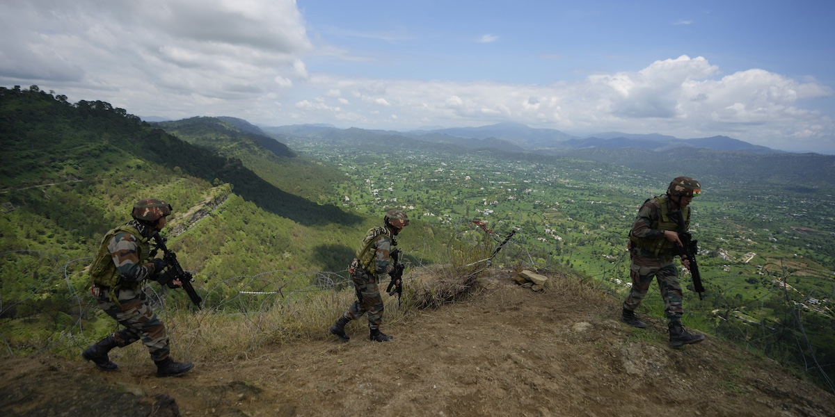 tre militari indiani in cima a una collina con sullo sfondo un paesaggio verde rurale