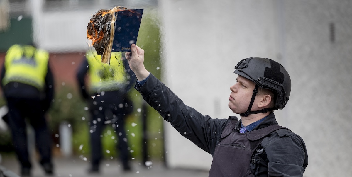 Rasmus Paludan mentre brucia una copia del Corano in una manifestazione in Svezia, nel maggio del 2022 (Jonas Gratzer/Getty Images)