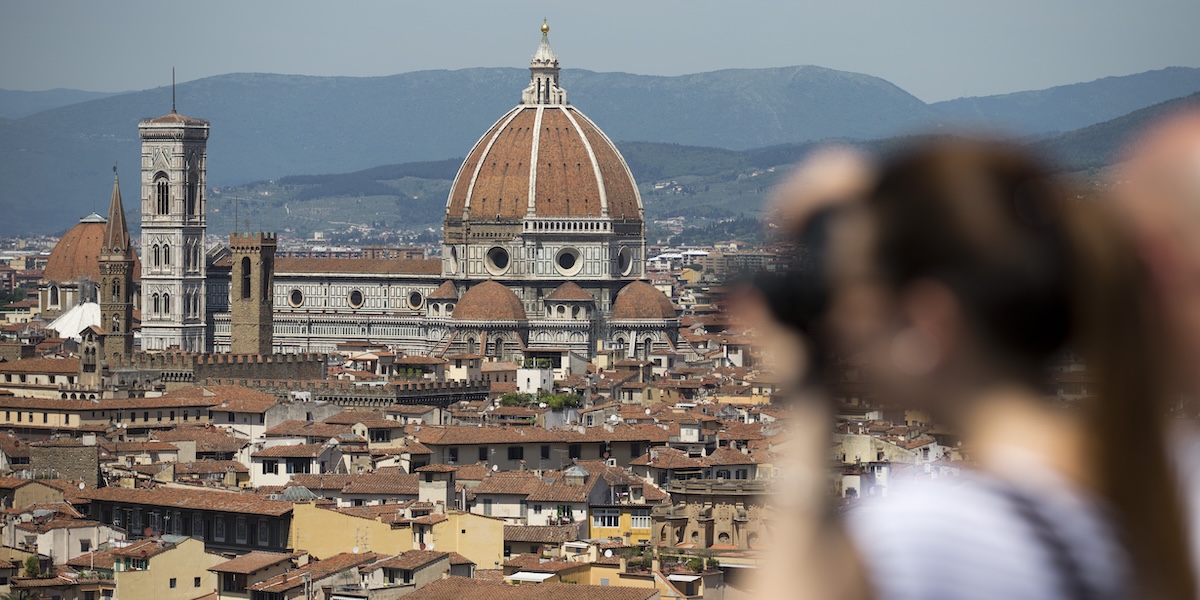 Santa Maria Novella, a Firenze, vista da lontano, con la sagoma di una turista che la fotografa in primo piano