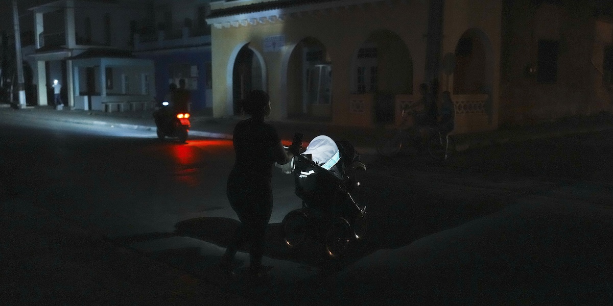 Una donna spinge un passeggino durante un blackout programmato nella città di Bauta, a Cuba, 18 marzo 2024 (AP Photo/Ramon Espinosa)