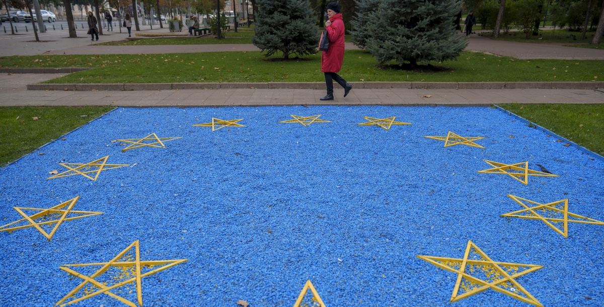 Una donna cammina vicino a una bandiera dell'Unione Europea fatta di ciottoli blu a Chisinau, in Moldavia, prima del voto (AP Photo/Vadim Ghirda)