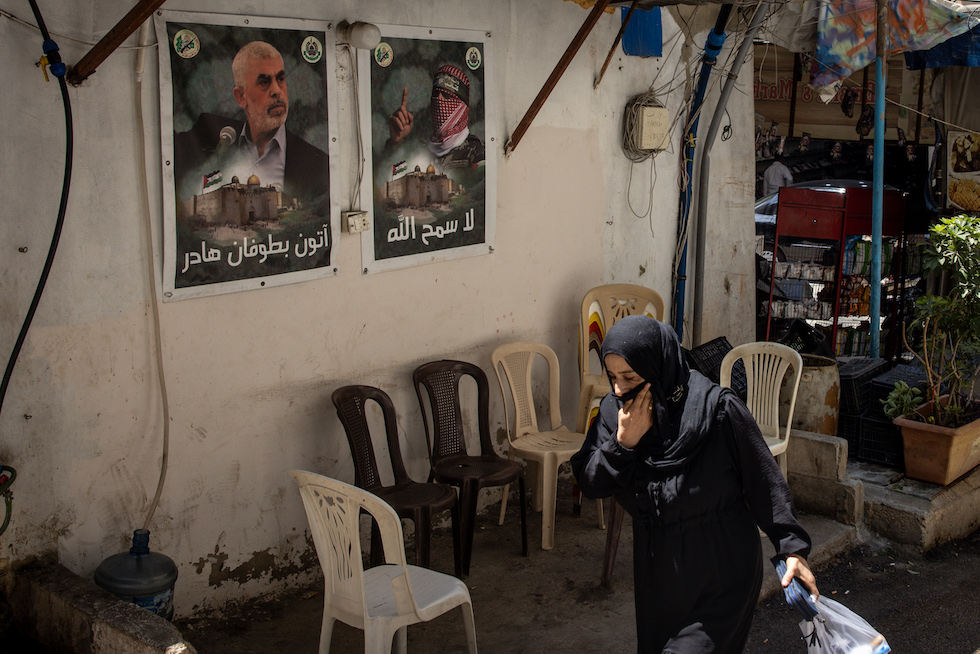 Una donna passa davanti a un poster di Yahya Sinwar nel campo profughi di Bourj al Barajneh a Beirut, in Libano