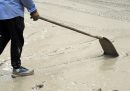 Un uomo spala il fango su una strada di Bologna