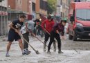 Persone al lavoro su una strada di Bologna coperta di fango