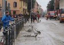 Persone al lavoro su una strada di Bologna coperta di fango