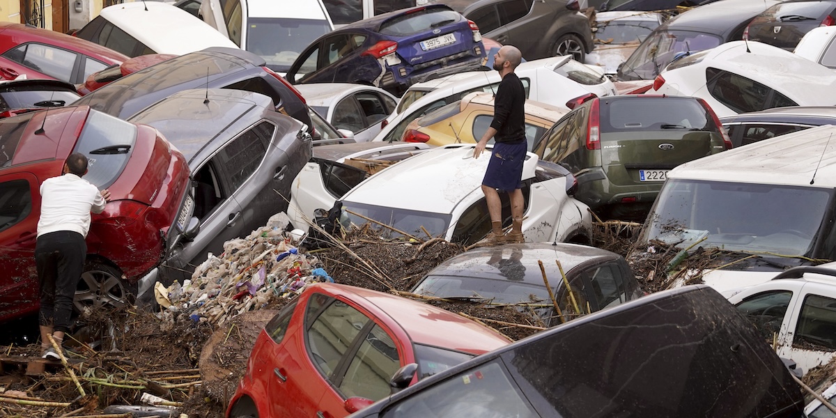 Un uomo fra le auto accatastate in una strada dall'alluvione a Valencia, il 30 ottobre 2024 (AP Photo/Alberto Saiz)