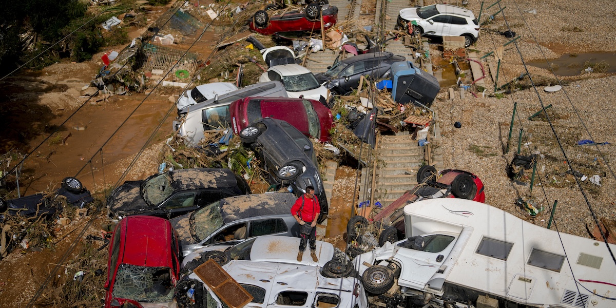 Un uomo su un cumulo di auto accatastate a Valencia, 31 ottobre (AP Photo/ Manu Fernandez)