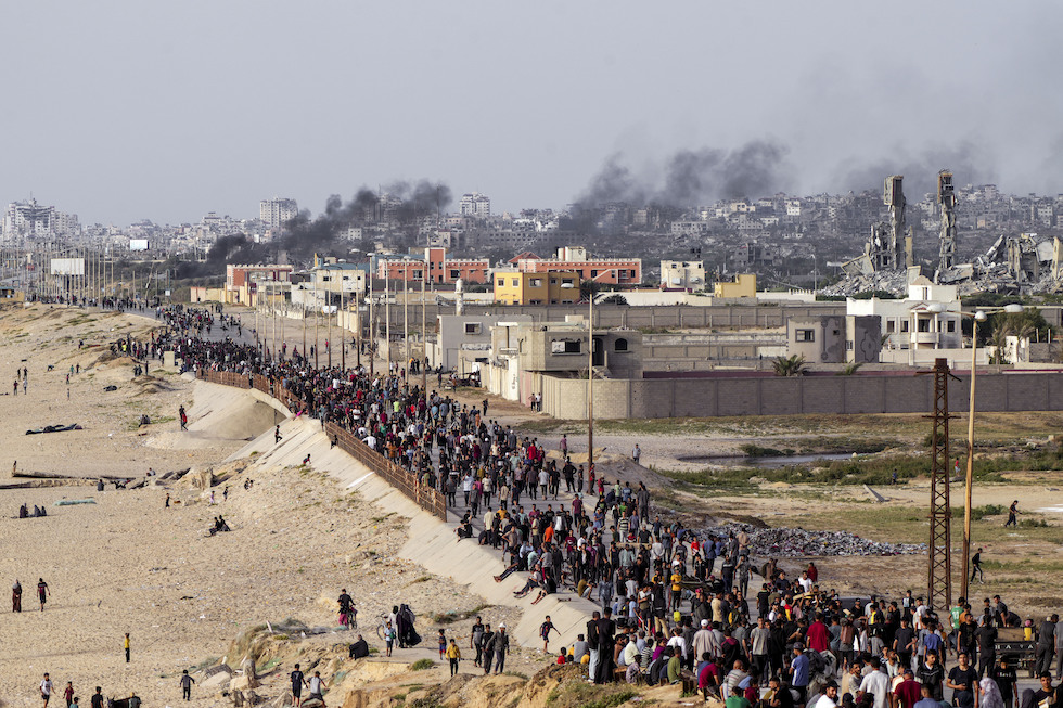 Persone palestinesi vicino al confine in attesa dai camion di aiuti 