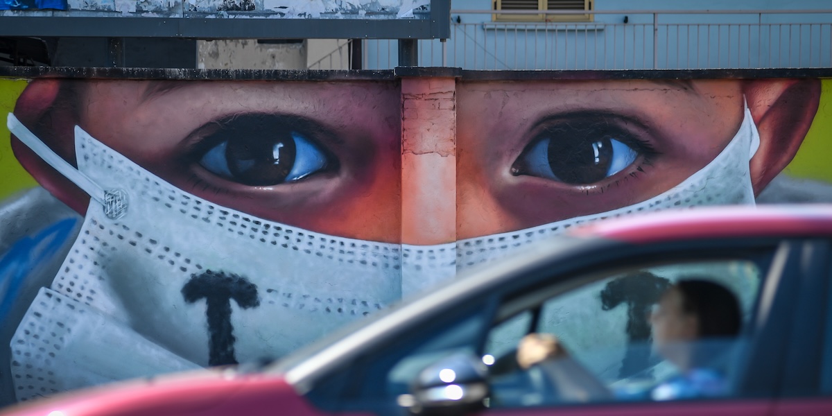 Una persona in auto davanti a un murale dedicato ai medici e al personale sanitario dell'ospedale Sacco di Milano