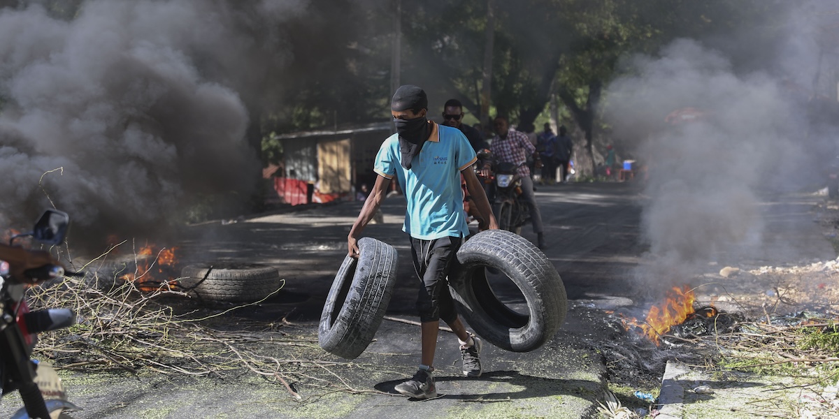 Un uomo raccoglie materiale per una barricata a difesa del proprio quartiere, Port-au-Prince, 19 novembre 2024 (AP Photo/Odelyn Joseph)